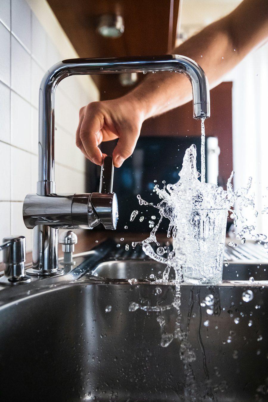 Clean water splashing from a kitchen tap into a glass